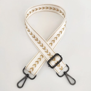 Adjustable beige nylon strap with gold arrow embroidery and black metal hooks
