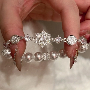 Elegant pearl bracelet with sparkling zircon snowflake charms on a soft white plush background