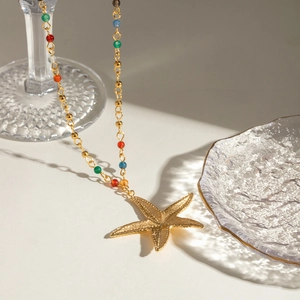 Macro detail of golden starfish pendant with textured finish and colorful gemstone beads