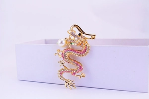 Detail of a golden dragon keychain featuring pink crystals and a white pearl accent