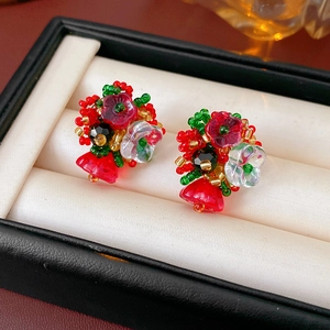 Close-up of handmade beaded flower earrings with red and green crystals on satin padding