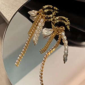 Détail de boucles d'oreilles dorées avec perles et glands en strass sur une surface miroir