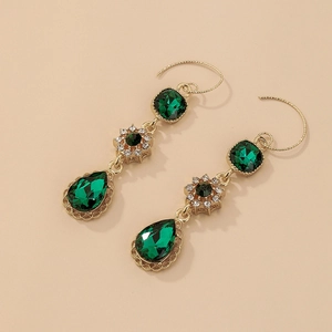 Close-up of vintage emerald green drop earrings with intricate gold floral details