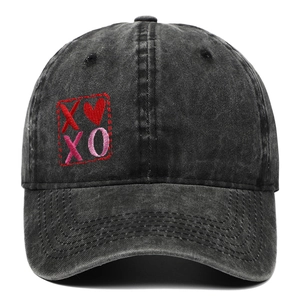 Dettaglio del ricamo a cuore XOXO rosso e rosa su un cappellino da baseball nero lavato