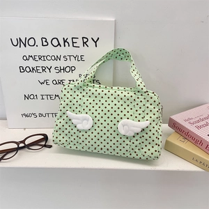 Close-up of a light green polka dot canvas bag with 3D plush wings and top handles