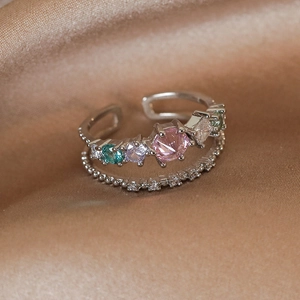 Macro shot of double-layered silver ring with colorful cubic zirconia on silk background