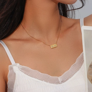 Detail of gold rectangular necklace pendant with 11:11 engraving and white rhinestones