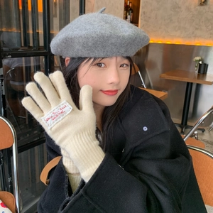 Close-up of off-white knitted touch screen gloves with red tag on female hand