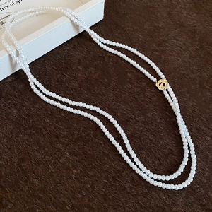 Detail of multi-layer pearl necklace featuring a golden floral OT toggle clasp closure