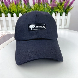 Detail of navy cotton baseball cap showing twill texture and handmade tree patch