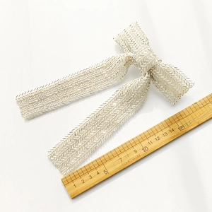 Detail of handmade bow hair clip with silver seed beads in a herringbone pattern