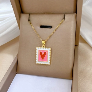 Detailed view of golden heart pendant with pink enamel and crystals in a luxury jewelry box