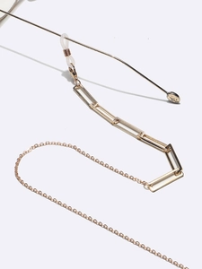 Detailed macro view of golden rectangular metal chain links for glasses and masks