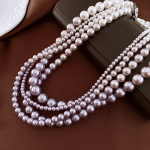 Detail of multi-layer white and purple gradient pearl necklace on a brown leather box