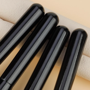 Detailed view of glossy black makeup brush handles with smooth piano finish and premium texture