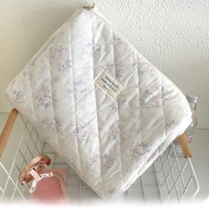Quilted floral makeup bag with pink flower pattern in a white metal basket setting