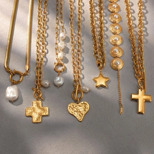 Detalle de collares de acero inoxidable dorado con perlas y cruces
