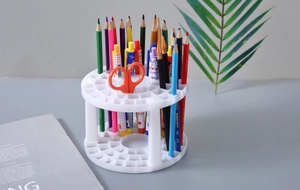 White multi-slot desk organizer holding pens and brushes on a modern minimalist desk
