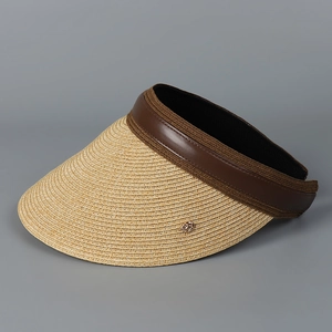 Close-up of beige woven straw sun hat with brown leather trim and gold metal detail