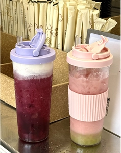 Detail of pink and purple Tritan tumblers with retractable straws and silicone sleeves