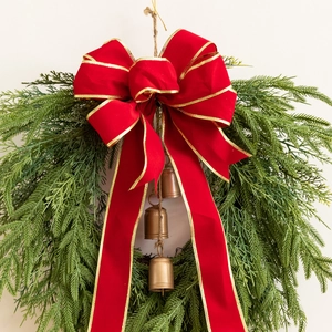 Close-up of Christmas wreath with red bow, pine needles and vintage bronze bells
