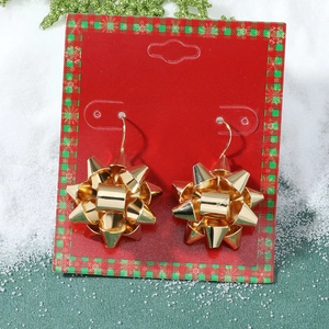 Vue macro de boucles d'oreilles nœuds dorés sur carte rouge avec décor de Noël