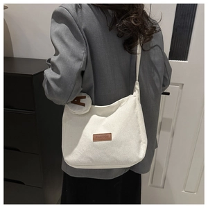 Detail view of white corduroy tote bag showing textured fabric and fashion brand tag
