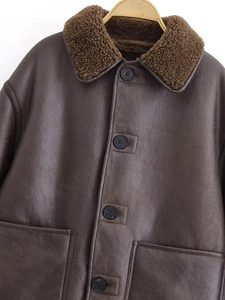 Detail of dark brown faux leather jacket featuring a soft sherpa collar and button closure