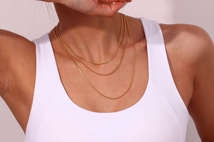 Detailed close-up of a triple-layered gold-plated stainless steel chain necklace on a model