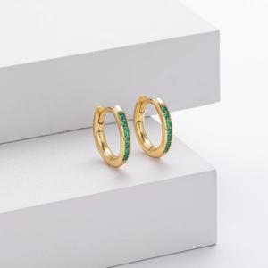 Close-up of gold s925 silver hoop earrings featuring green zircon stones on white cubes