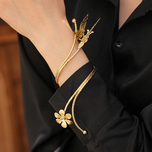 Close-up of a gold butterfly and flower open bangle with rhinestone detail on a model