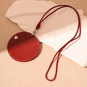 Detail of red circular PU leather keychain with white stitching and silver metal buckle