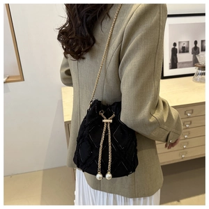 Quilted denim bucket bag with gold chain and pearl drawstring on model in green suit