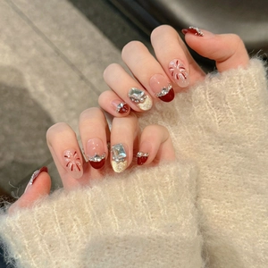 Gros plan sur des faux ongles rouge vin avec strass brillants et motifs feu d'artifice