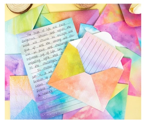 Close-up of watercolor gradient envelopes and lined stationery with textured paper detail