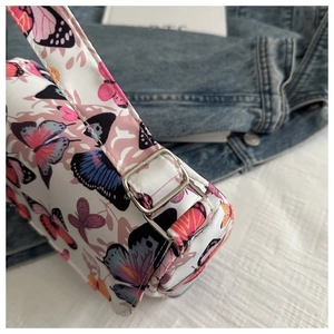 Detail of silver metal buckle and butterfly print on a white stylish shoulder bag