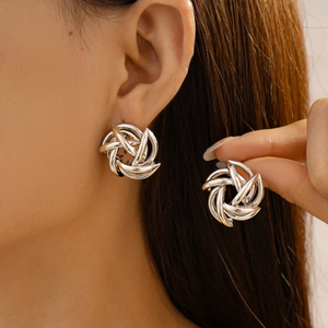 Close-up of silver geometric hollow flower swirl earrings with metallic luster on model