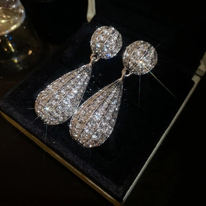 Macro shot of silver drop earrings with pavé crystals in a black velvet jewelry box