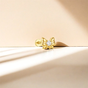 Macro shot of gold bowknot flat back stud earring with a central clear zircon inlay