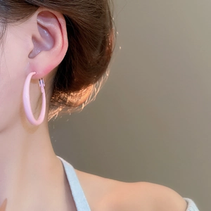 Close-up of a pink hoop earring worn by a model showcasing its glossy minimalist texture