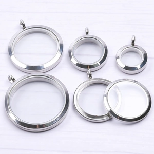 Macro view of various sizes of stainless steel floating locket pendants on white wood