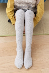 Detailed texture of thick light grey coral fleece over-the-knee socks on a person