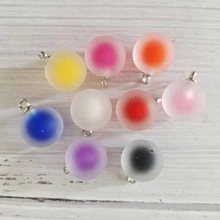 Close-up of frosted 16mm star glass ball pendants with silver metal loops in various colors