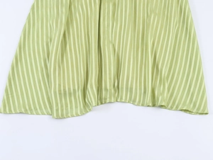 Detail of green striped fabric hem with subtle sheen and elegant drape on the dress