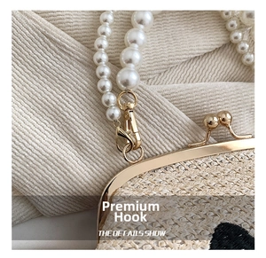 Détails d'un sac en paille tissée avec bandoulière en perles et fermoir doré chic