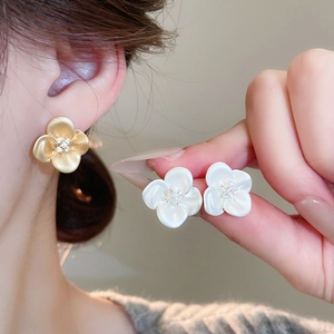 Close-up of elegant flower stud earrings featuring micro-set cubic zirconia and golden finish
