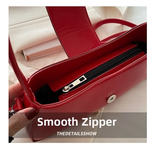 Detail view of smooth metal zipper and magnetic closure on the red crescent bag