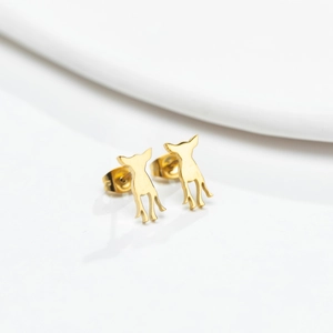 Minimalist golden dog silhouette stud earrings with polished metallic finish on white stand
