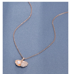 Detail of 18k rose gold necklace with shell pendant, inset pearl and sparkling crystals