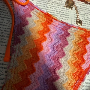 Colorful crochet zigzag bikini top with vibrant bohemian patterns and heart charm